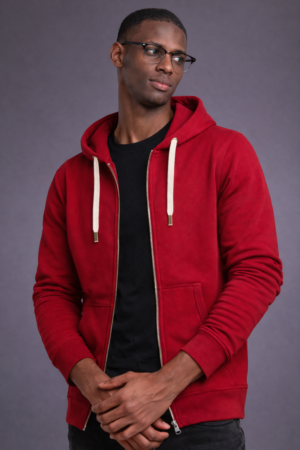Man wearing a red hoodie over a black shirt on a gray background