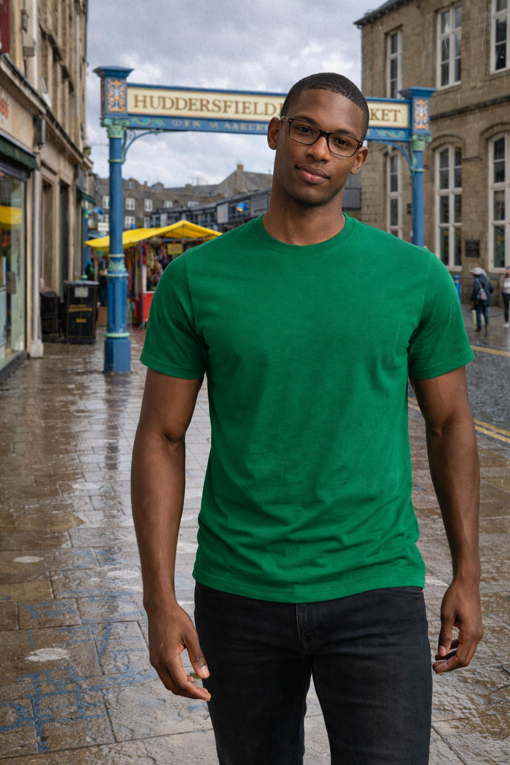Man wearing a green t-shirt standing in front of Huddersfield Market sign.