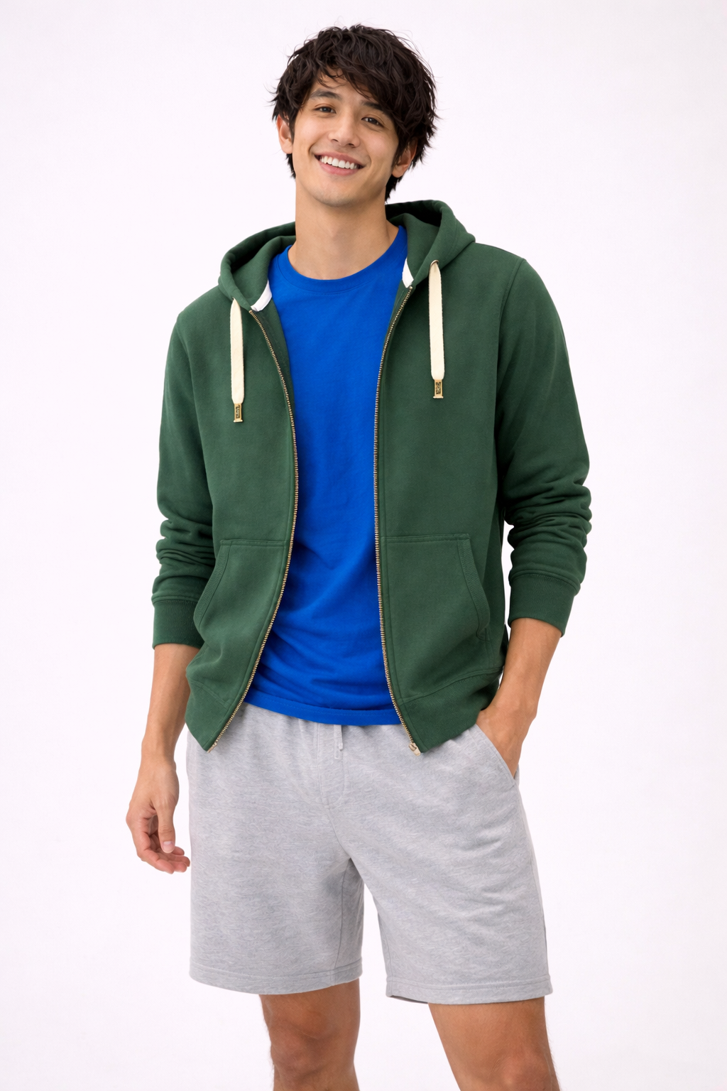 Man wearing a green hoodie, blue shirt, and gray shorts on a white background