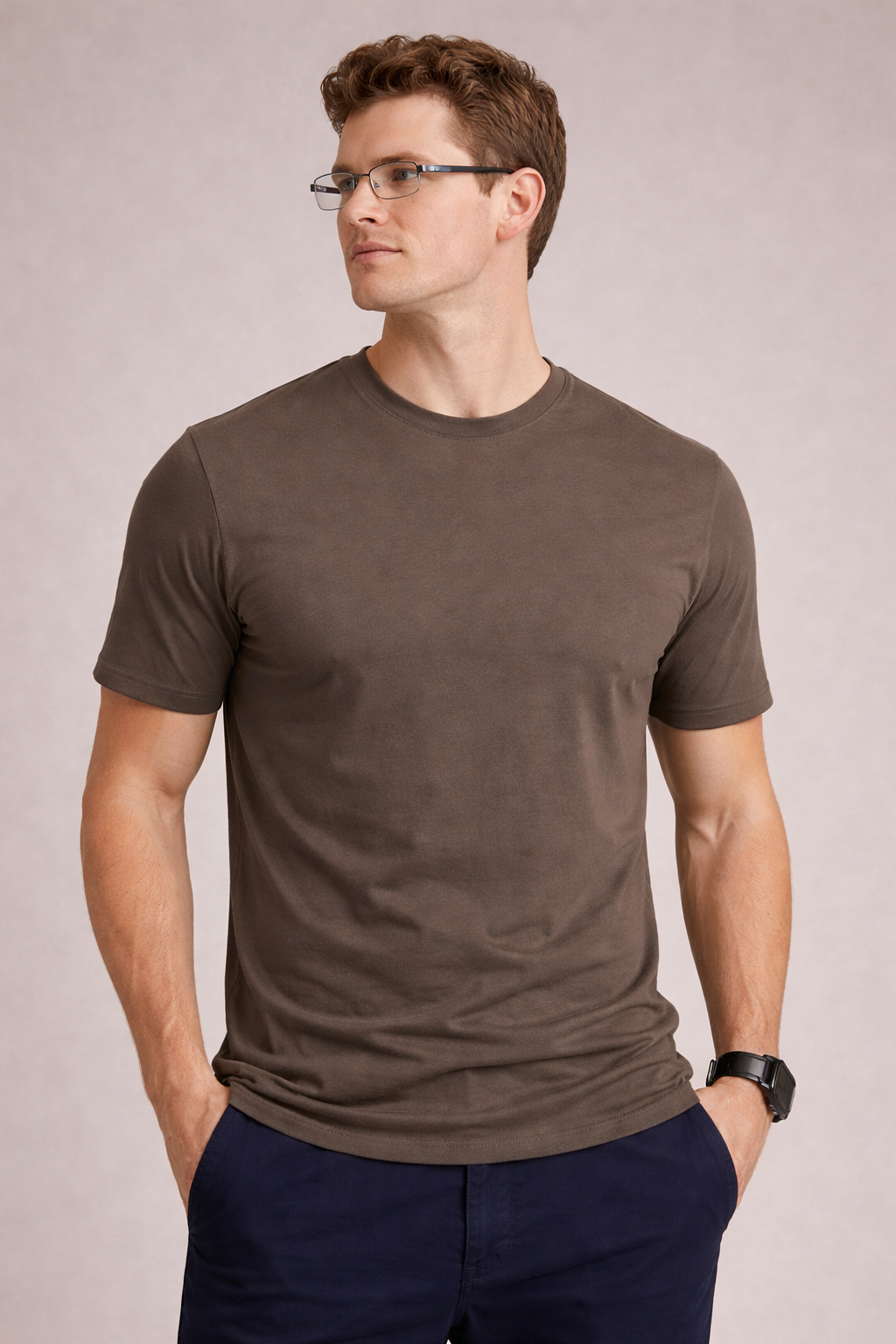 Man wearing a brown t-shirt and glasses against a plain background