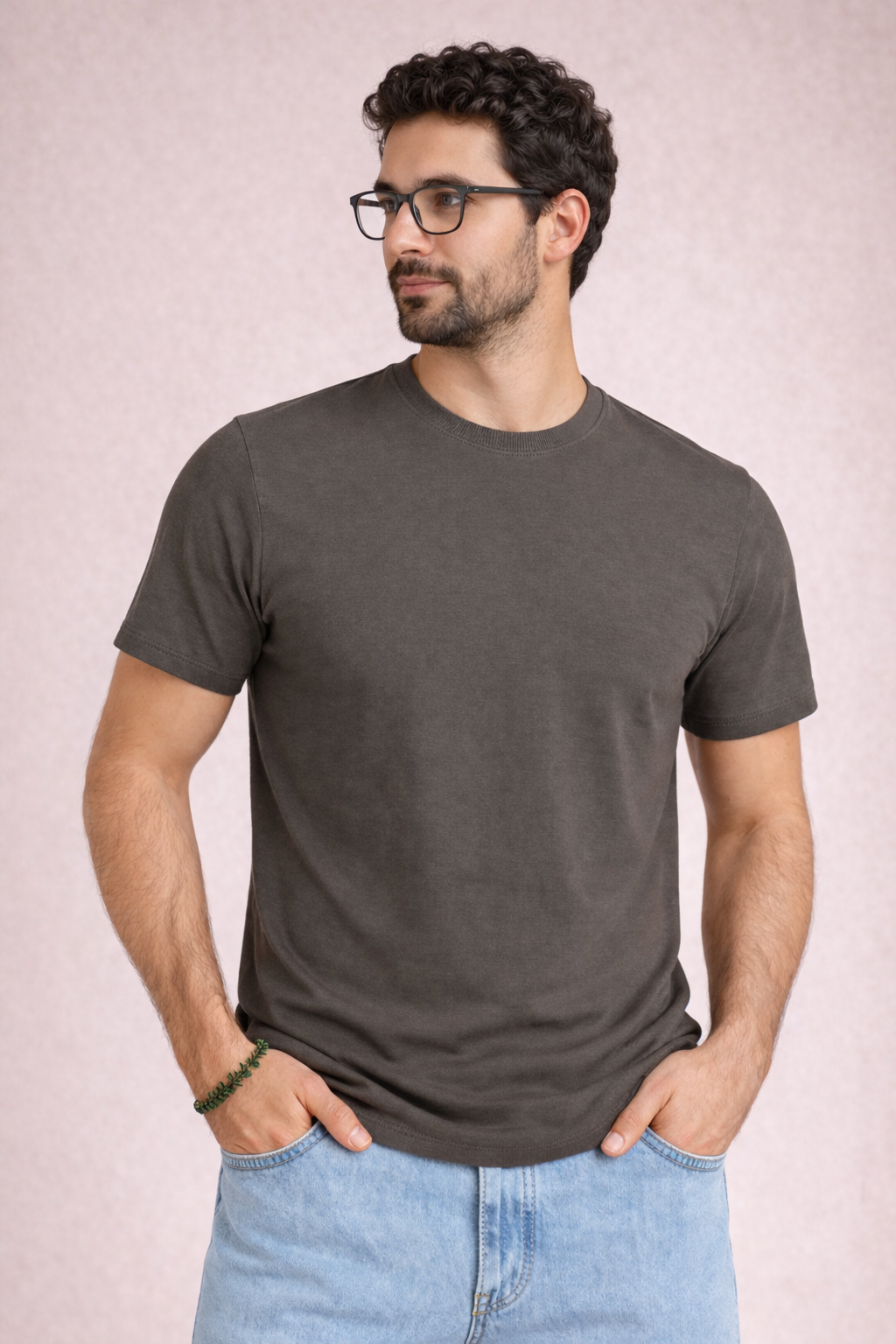 Man wearing a dark gray t-shirt and light blue jeans against a plain background