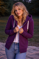 Woman wearing a purple hoodie outdoors with a blurred natural background