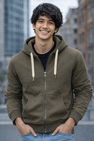 Man wearing a green hoodie with a blurred cityscape background