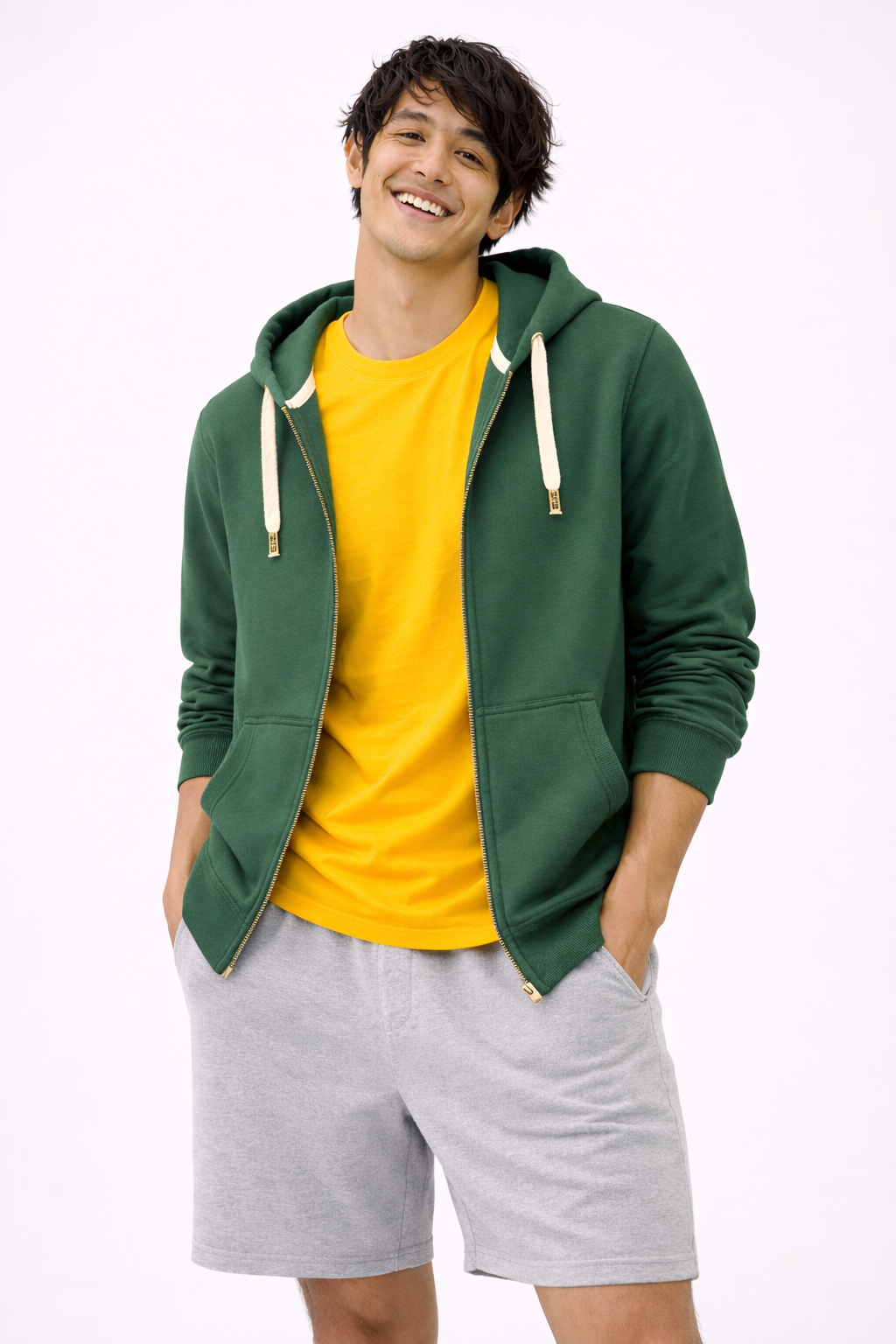 Man wearing a green hoodie, yellow shirt, and gray shorts on a white background