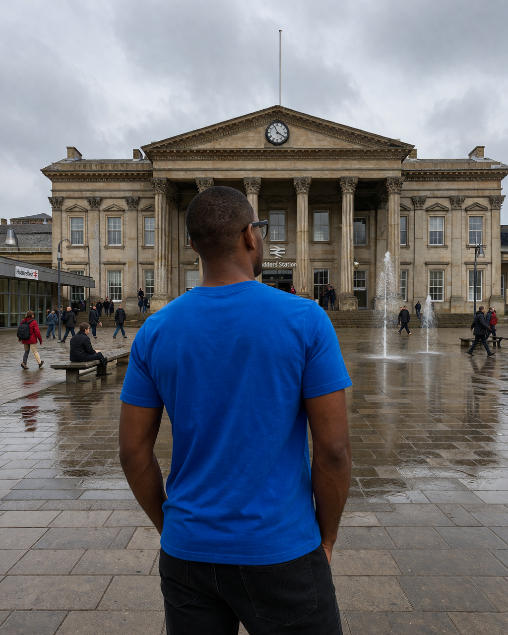 Man in a blue shirt standing in front of a large building with columns on a cloudy day.