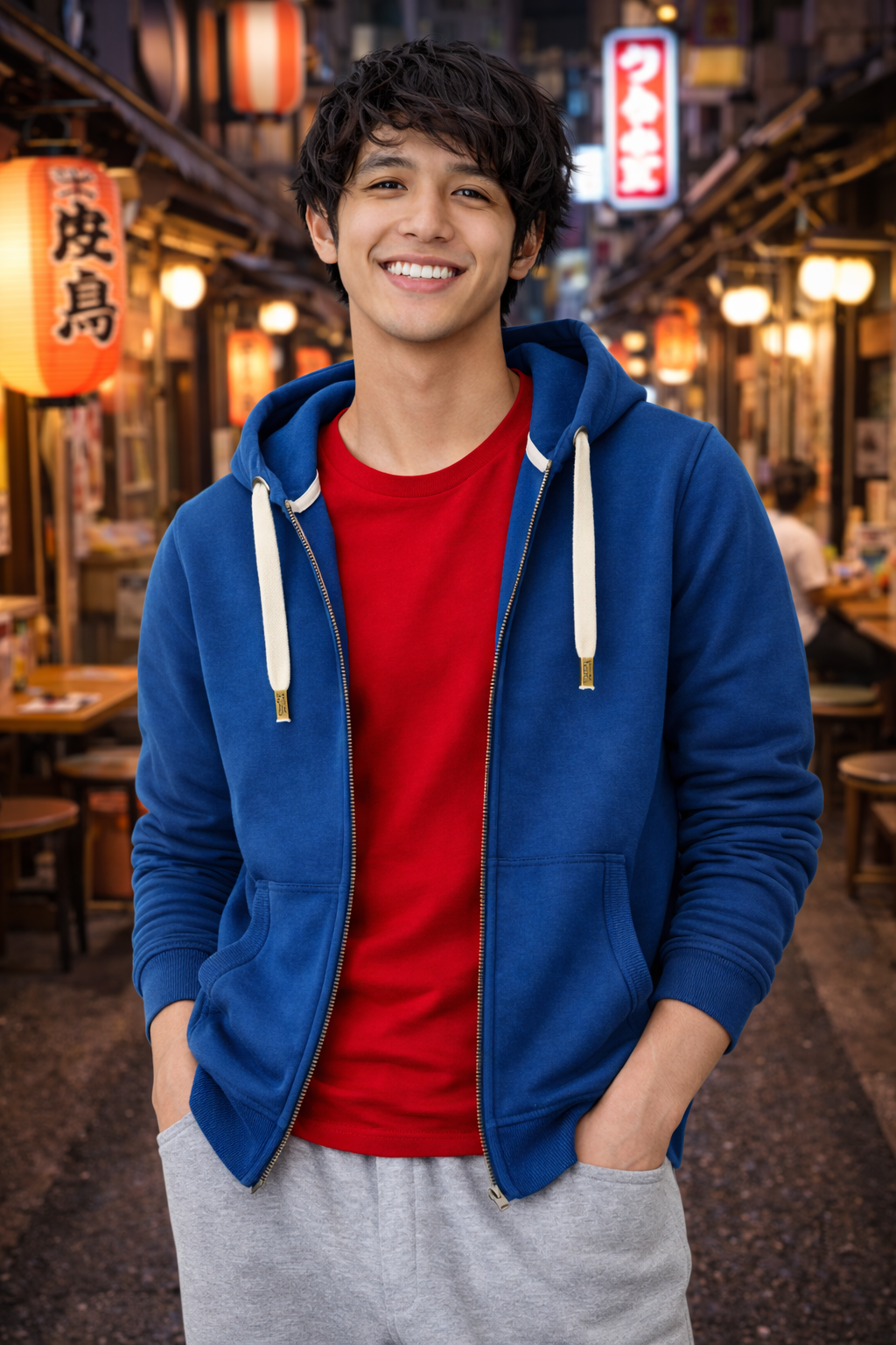 Person wearing a blue hoodie over a red shirt with a casual pose in an urban setting.